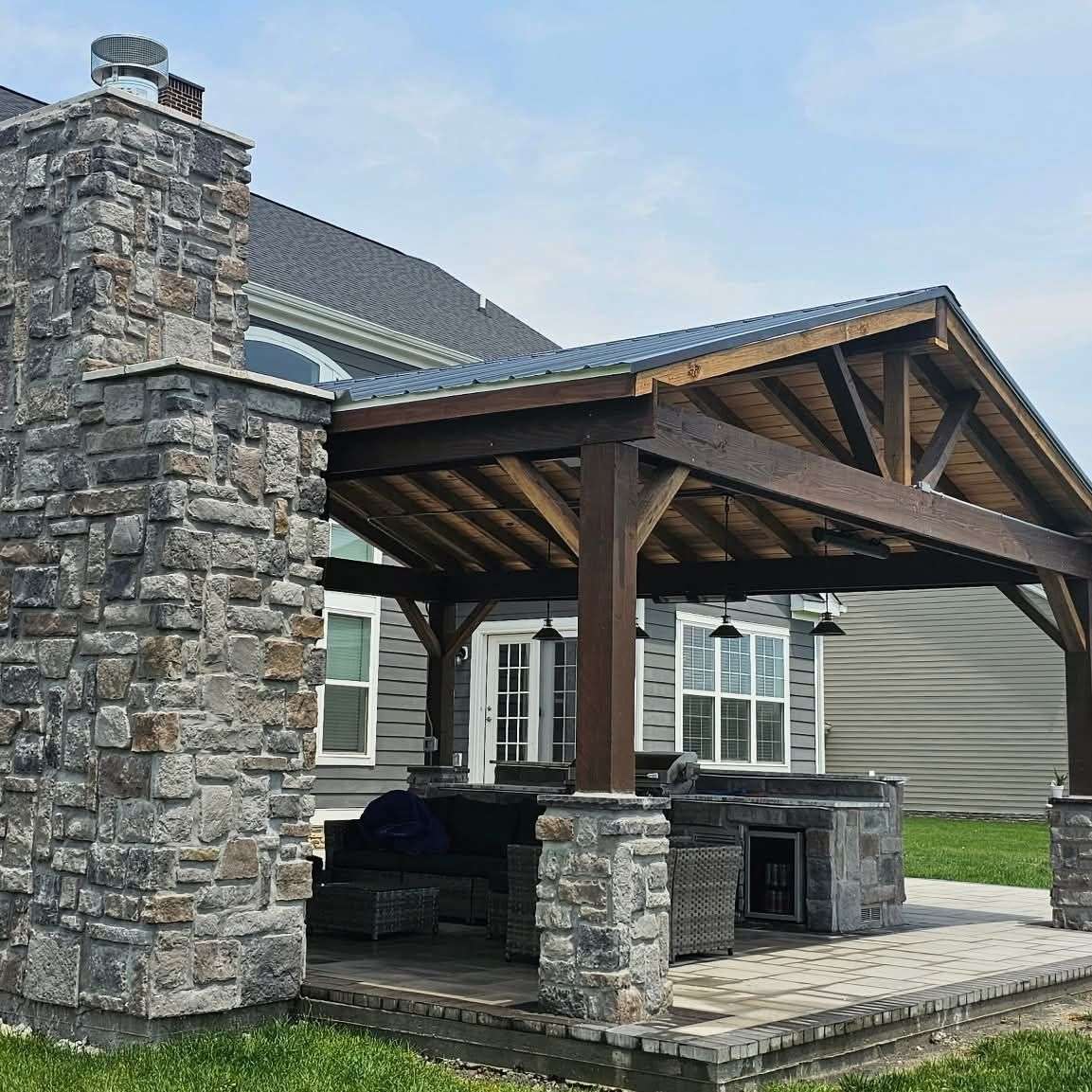 Cedar pavilion with a tall stacked-stone chimney and stone piers