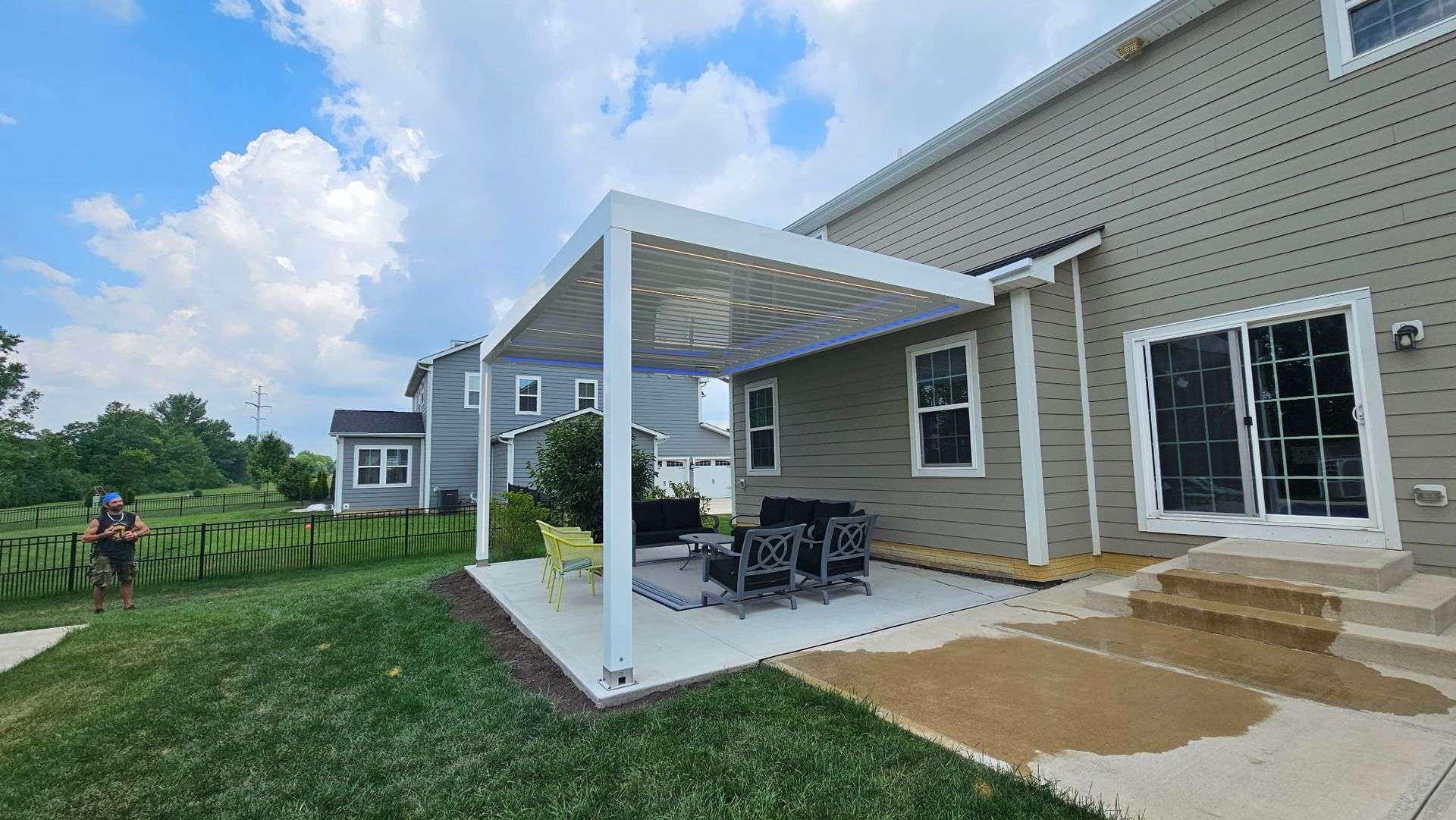 White louvered pergola attached to a house over a patio with outdoor furniture